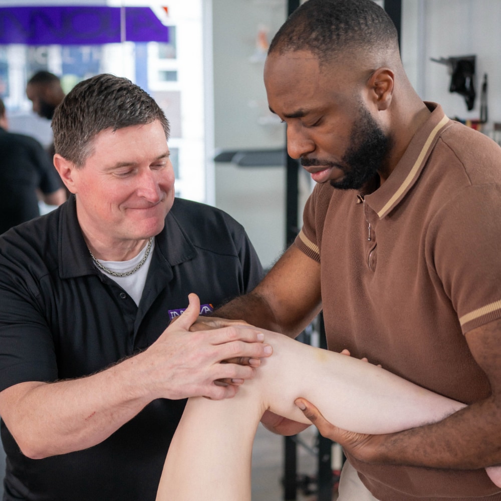Two therapists examine a patient's knee