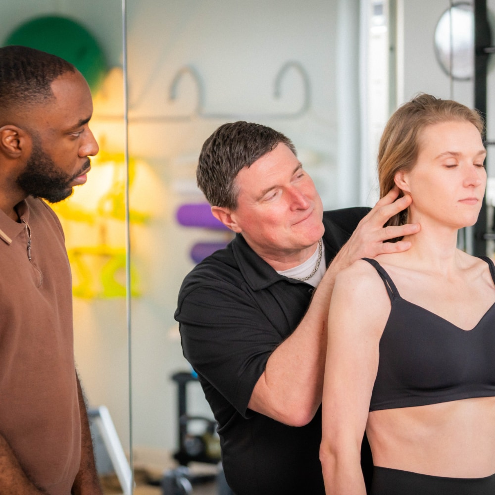 Bret examines a patient's neck while another therapist observes