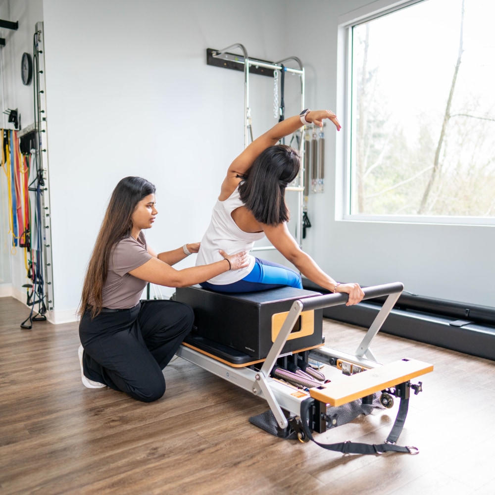 A therapist assists a patient with a seated side stretch
