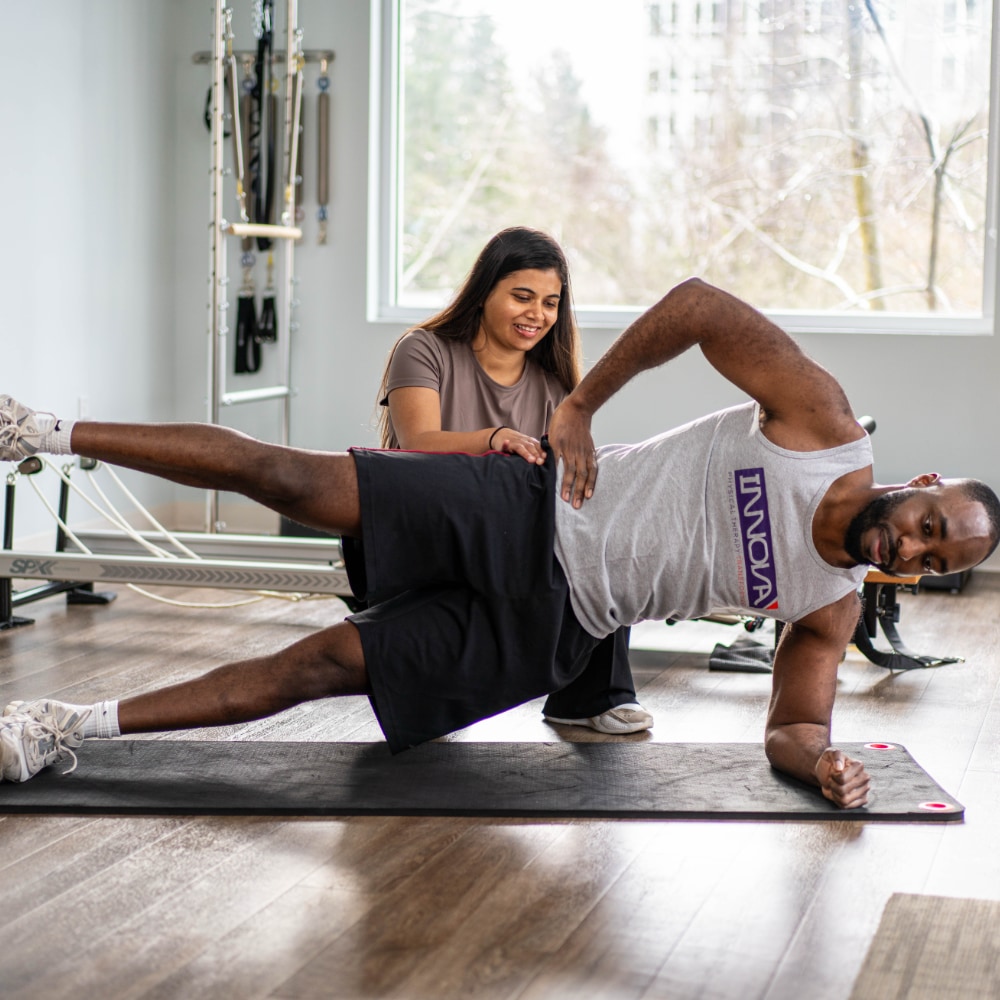 A patient does a side plank with assistance from a therapist