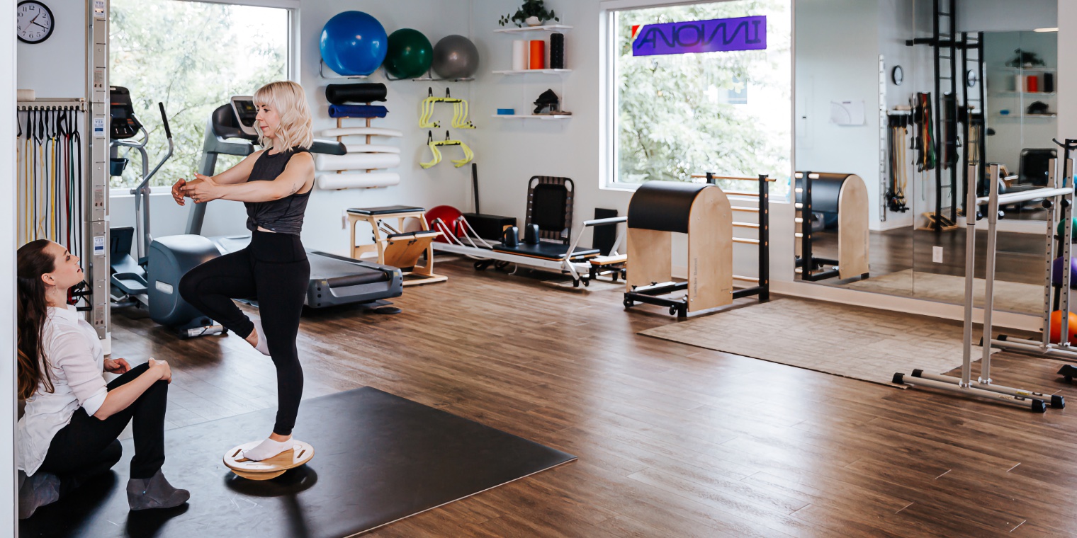 panoramic photo of a gym area with practitioner watching a patient on a balance device